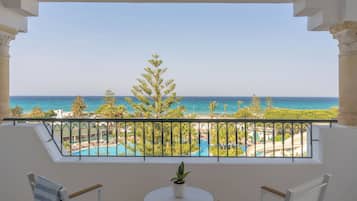A balcony with a view of a pool and the sea.