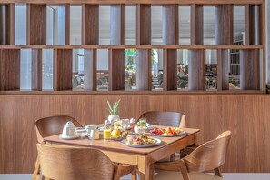 Une table de petit-déjeuner avec une table en bois, des chaises et une vue à travers une cloison en bois.