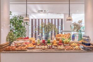 Ein reichhaltiges Buffet mit verschiedenen Speisen und Getränken, umgeben von Pflanzen und dekorativen Vasen.