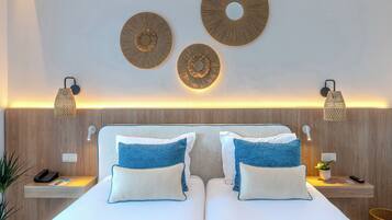 Una habitación de hotel con una cama doble, dos mesitas de noche, una lámpara de pared y decoración mural.