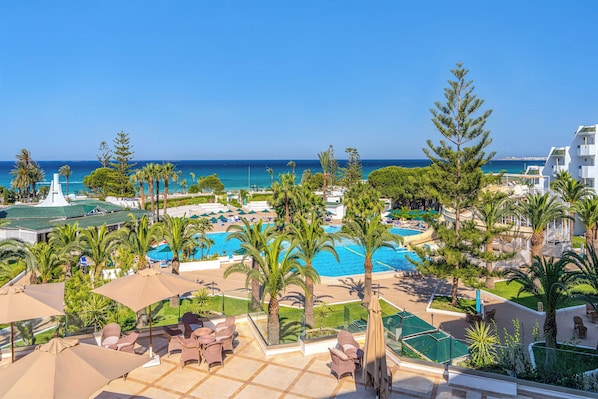 Un complexe hôtelier doté de plusieurs piscines, de palmiers et offrant une vue sur la mer.