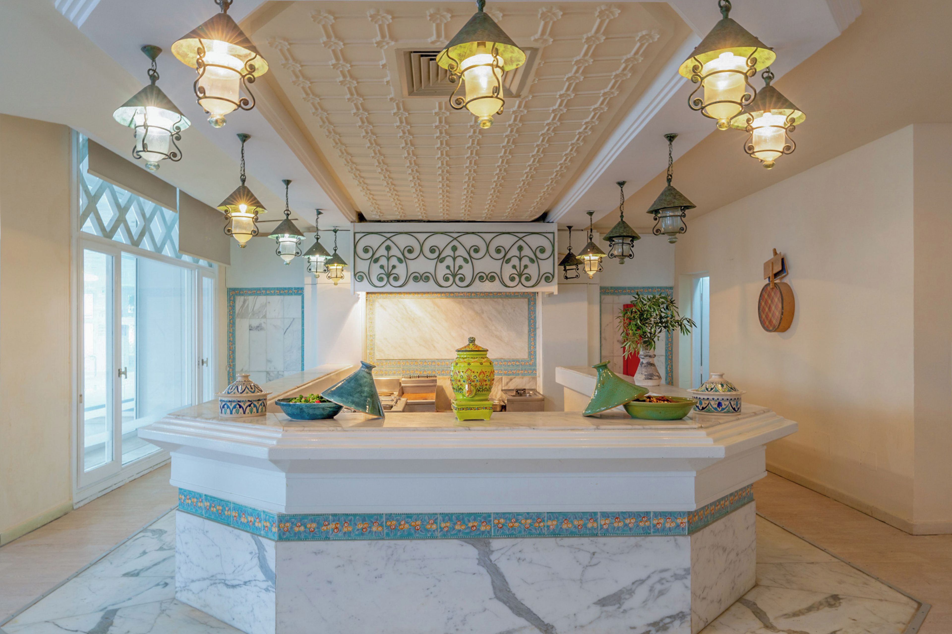 A marble-floored lobby with a central island, decorative lighting, and a large window.