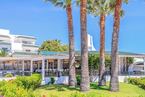 Ein Resort mit überdachter Außenbereich, Palmen und einem Gebäude mit grüner Dachbegrünung.
