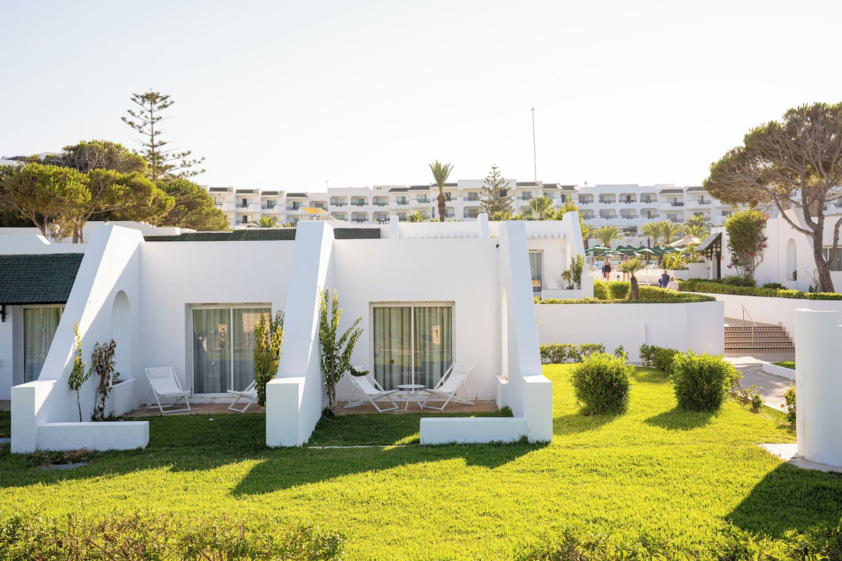 Un hotel moderno con arquitectura blanca, asientos exteriores y un césped bien cuidado.