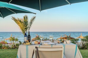 Ein Esszimmer im Freien mit Meerblick, eine Weinflasche und ein Glas Wasser.