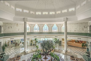 Eine großzügige Lobby mit einem zentralen Atrium, Marmorböden und einem Empfangsbereich.