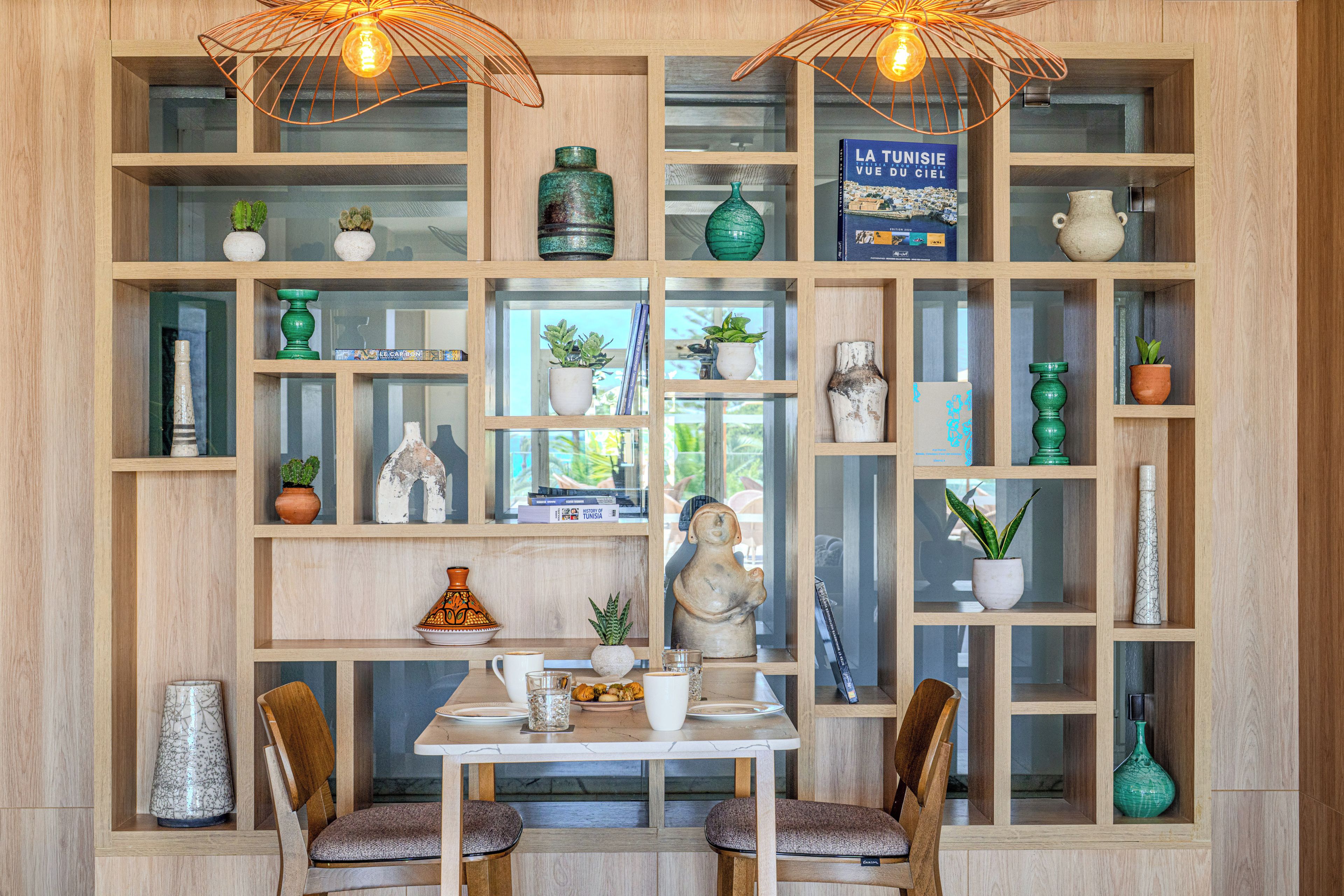 A room with a wooden shelving unit, a dining table with chairs, and various decorative items.