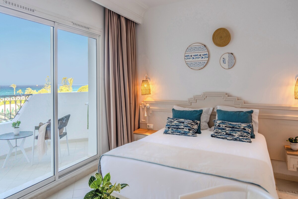 Ein Hotelzimmer mit Bett, einem Balkon und Blick sowie einer Wand mit dekorativen Tellern.