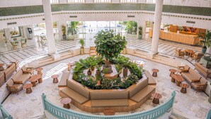 Un lobby espacioso con una zona de estar central, diversas opciones de asientos y una escalera.