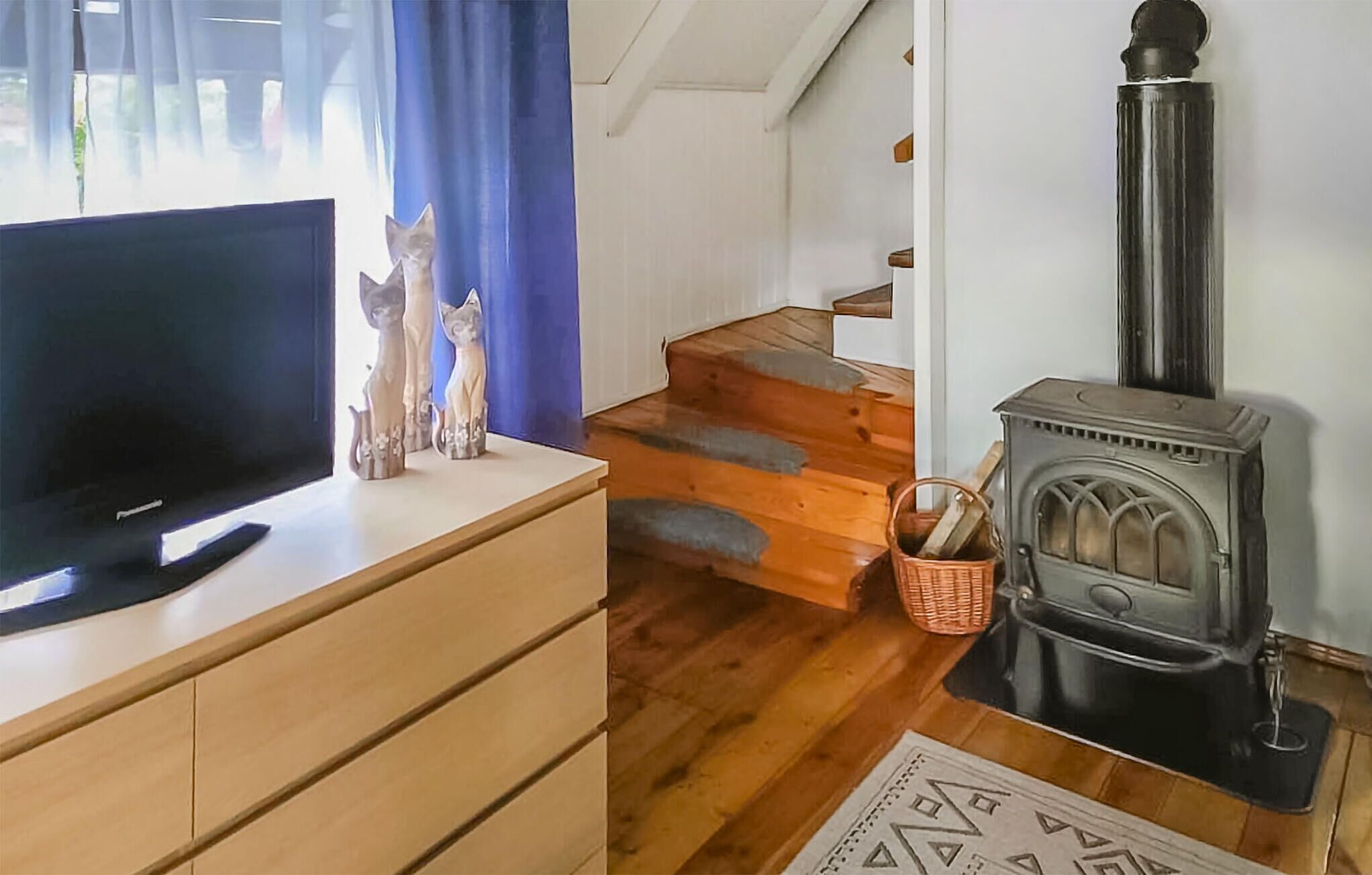 A cozy living room with a TV, a fireplace, and a staircase.