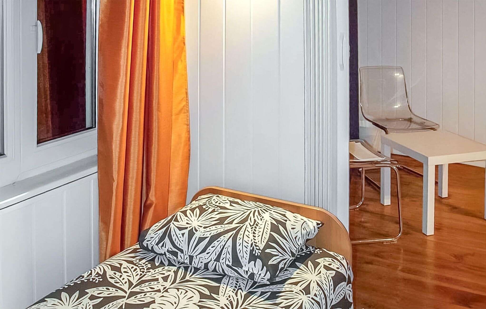 Ein kleiner Raum mit einem Bett, einem Sessel und einem Tisch.