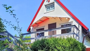 Een huis met een rood dak, een klein raam en een overdekte veranda.