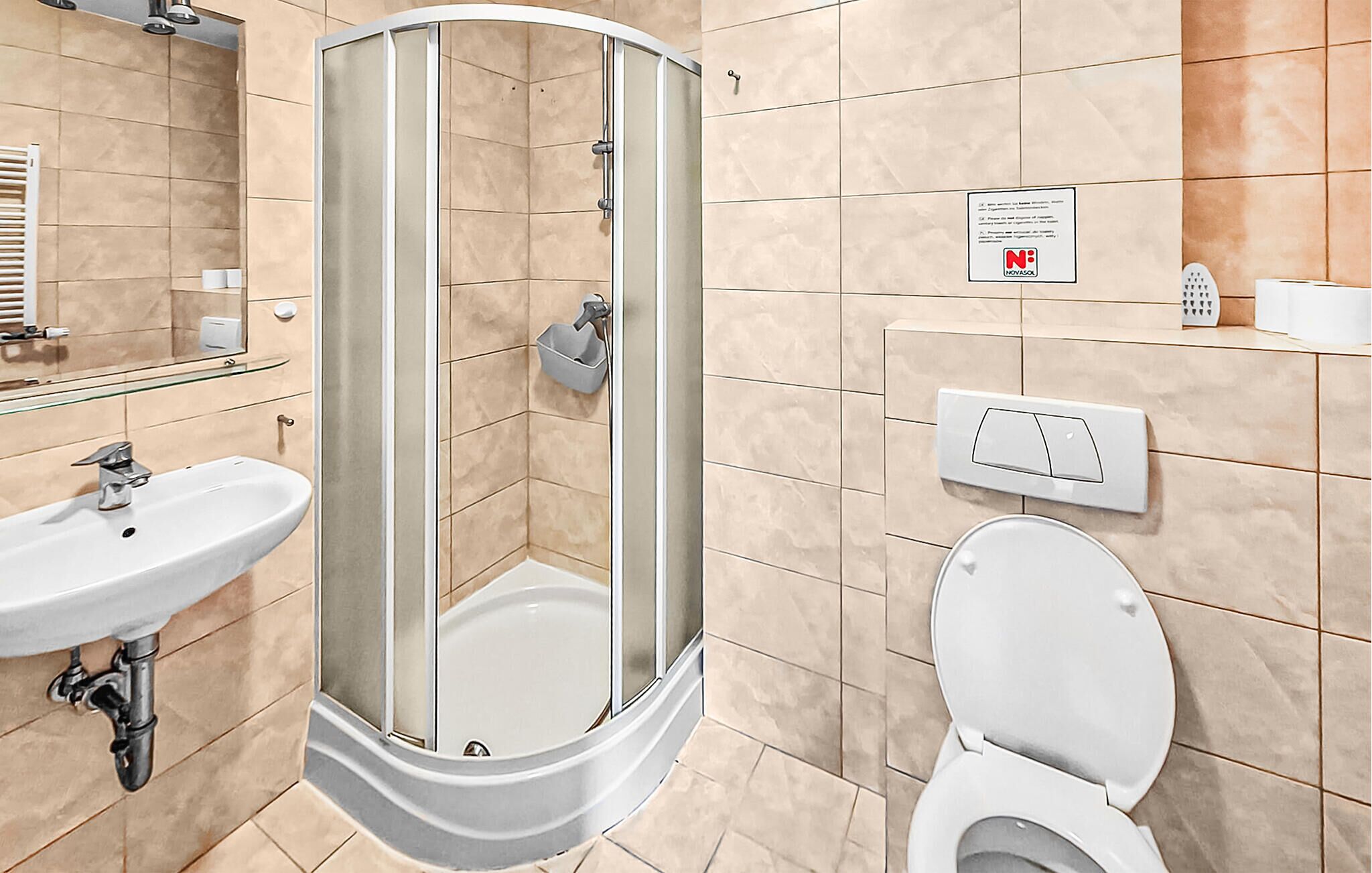 A bathroom with a glass-enclosed shower, a sink, a toilet, and a mirror.