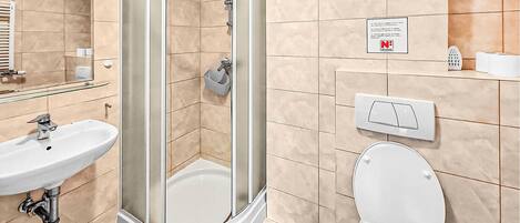 A bathroom with a glass-enclosed shower, a sink, a toilet, and a mirror.