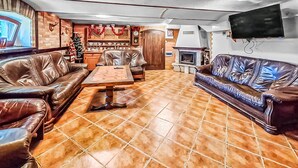 A living room with leather sofas, a coffee table, a fireplace, and a television mounted on the wall. - Amazing apartment in Szyldak with sauna (Szyldak)