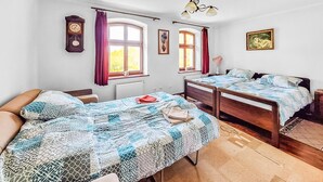 A bedroom with two beds, a wooden headboard, a window with curtains, a wall clock, and a framed picture. - Amazing apartment in Szyldak with sauna (Szyldak)