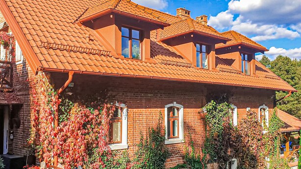 A two-story house with a red-tiled roof, brick walls, and multiple windows. - Amazing apartment in Szyldak with sauna (Szyldak)