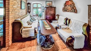 A traditional living room with a brick wall, a wooden coffee table, and two sofas with patterned throw pillows. - Amazing apartment in Szyldak with sauna (Szyldak)