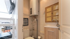 A compact bathroom with a toilet, a sink, a shower, and a towel rack.