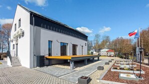 A modern building with a flat roof, large windows, and a covered outdoor seating area.