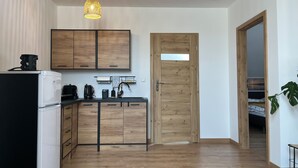 A modern kitchen with wooden cabinets, a black refrigerator, and a wooden door.