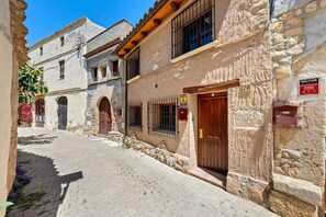 Una estrecha calle adoquinada bordeada por edificios históricos de piedra con puertas de madera y rejas.