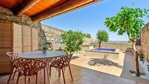 Un patio al aire libre con una mesa redonda y sillas, un muro de piedra y vistas al paisaje.
