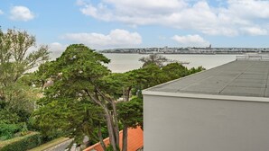 Une vue sur la côte, avec un bâtiment, des arbres et une silhouette de ville en arrière-plan.