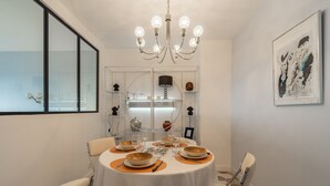Un coin repas avec une table ronde, des chaises, un lustre et une œuvre d’art encadrée accrochée au mur.