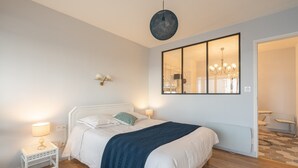 Une chambre à coucher moderne avec un grand lit, des lampes de chevet, un lustre et une vue sur la salle de bain.