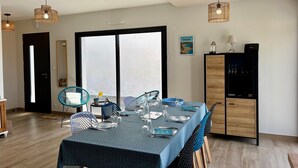 Un coin repas avec une table dressée pour quatre personnes, une grande fenêtre et un meuble contenant un téléviseur.