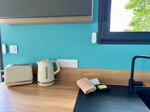 A kitchen with a toaster, kettle, and a sink with a towel and soap.