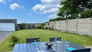 Eine Terrasse mit Esstisch, umgeben von Stühlen, einer kleinen Pflanze und einer Steinsäule.