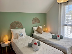 Habitación doble con dos camas, cada una con cubrecama estampado con estrellas, una lámpara de noche y una mesita con un libro.