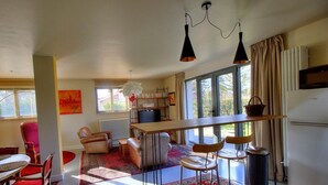 A modern kitchen with a dining area, large windows, and a view of the outdoors. - La Maison de Craponne (CRAPONNE)