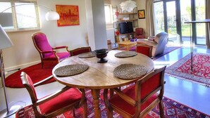 A dining area with a round wooden table, red upholstered chairs, and a red carpet. - La Maison de Craponne (CRAPONNE)