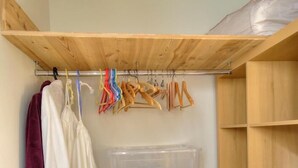 A closet with wooden shelves, a hanging rod, and a plastic storage box. - La Maison de Craponne (CRAPONNE)