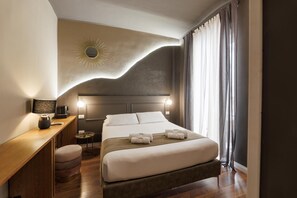 Una camera d'albergo con un letto, un comodino, una lampada e vista sull'esterno.
