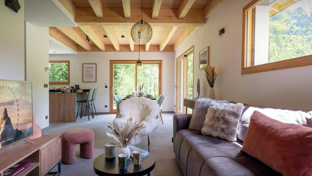 Un salón amplio con techo de madera, un comedor y ventanas grandes.