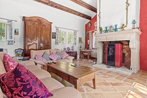 A living room with a sofa, coffee table, fireplace, and wooden beams on the ceiling. - Bastide Lou Pèbre d'Aï - Scent of Lavender (La Roquebrussanne)