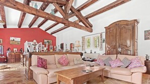 Amplia sala de estar con un gran techo de madera, un conjunto de sofá color beige, una mesa de centro de madera y un suelo de baldosas de piedra.