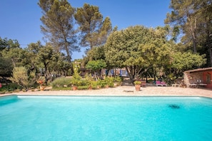 A pool with clear water, surrounded by trees and a building with a red roof. - Bastide Lou Pèbre d'Aï - Scent of Lavender (La Roquebrussanne)