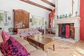 Una sala de estar con sofá, mesa de centro, chimenea y vigas de madera en el techo.