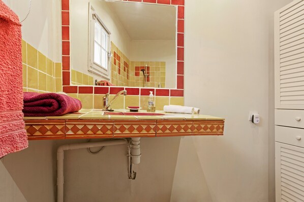 A bathroom with a sink, mirror, and towel rack.