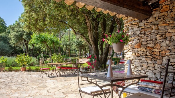 An outdoor patio with stone flooring, metal furniture, and a stone wall.