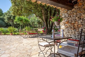 Un patio al aire libre con suelo de piedra, mobiliario de metal y una pared de piedra.