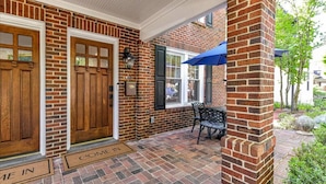 A brick exterior with a wooden door and a window with a blue umbrella.