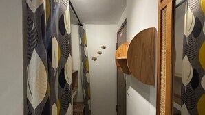 Een smalle gang met behang, een houten plank en een betegelde vloer.