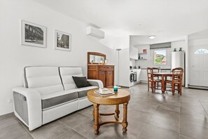 Un salon moderne avec un canapé, une table basse en bois et un coin repas avec des chaises.