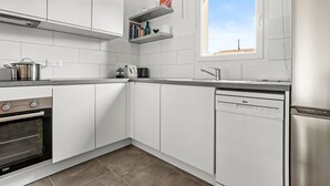 A modern kitchen with white cabinets, a built-in oven, a dishwasher, and a window with a view. - Villa 'Les Coteaux Du Soleil' with Private Pool, Wi-Fi and Air Conditioning (Carcès)